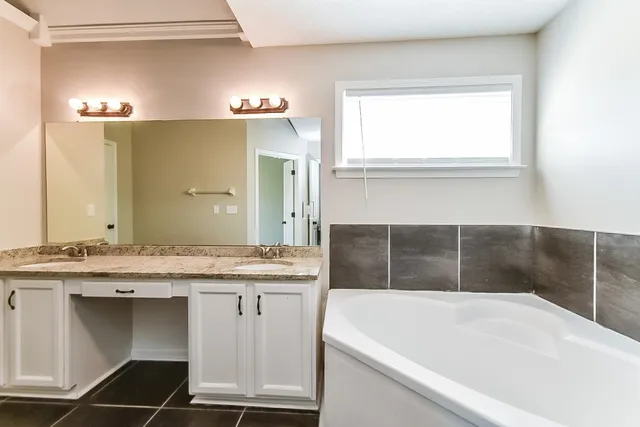 a bathroom with a granite countertop sink a bathtub and a mirror