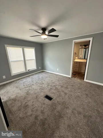 an empty room with windows and ceiling fan