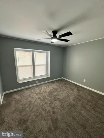 an empty room with windows and ceiling fan