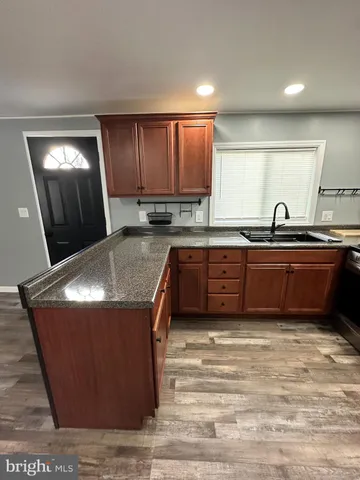 a kitchen with kitchen island granite countertop a sink a counter top space and cabinets