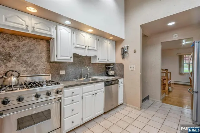 a kitchen with granite countertop a refrigerator and a stove top oven