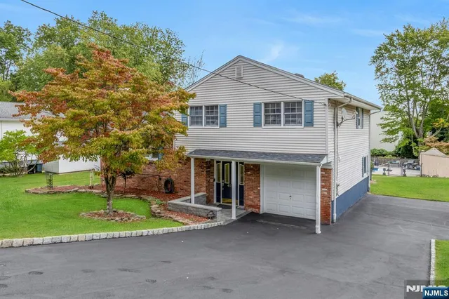 a view of a house with a yard and large tree