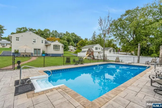 a view of swimming pool with lawn chairs and plants