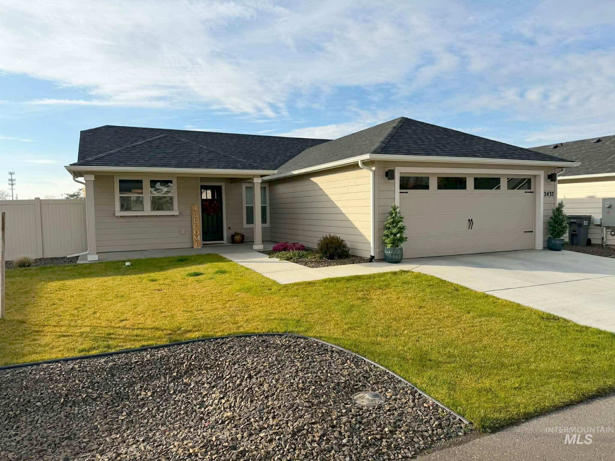 Single story home featuring a front lawn, driveway, an attached garage, roof with shingles, and covered porch