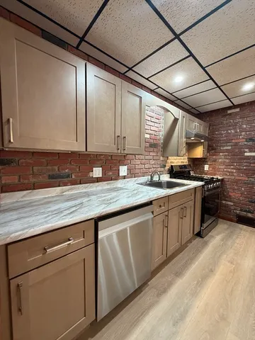 a kitchen with granite countertop a sink a counter space appliances and cabinets