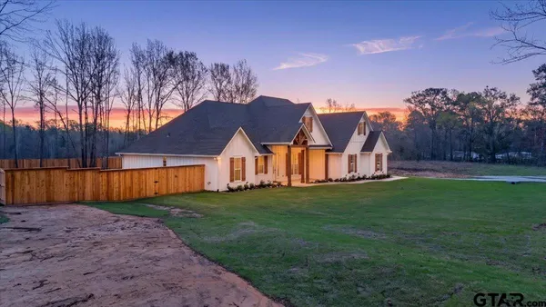 a view of a big house with a big yard and large trees