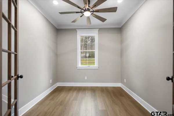 a view of an empty room with wooden floor and a kitchen