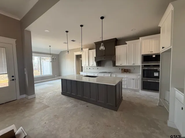 a large kitchen with stainless steel appliances kitchen island granite countertop a stove a sink a refrigerator and a granite counter tops