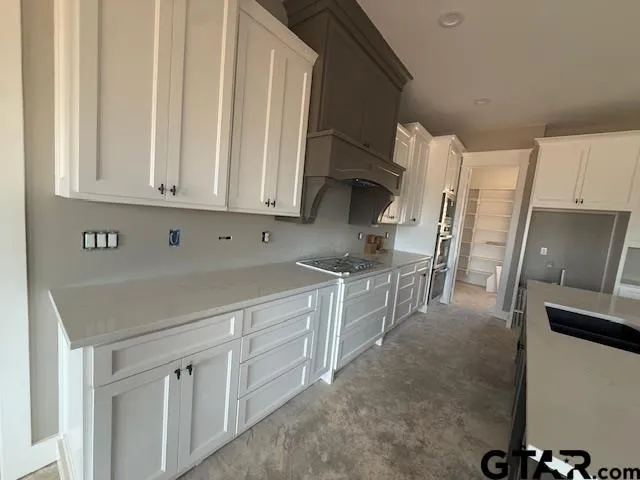 a kitchen with stainless steel appliances granite countertop a refrigerator sink and white cabinets