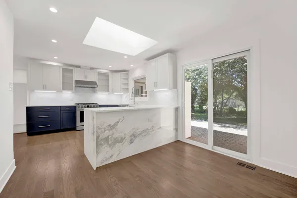 a kitchen with stainless steel appliances granite countertop a stove a refrigerator a sink and a oven with wooden floors