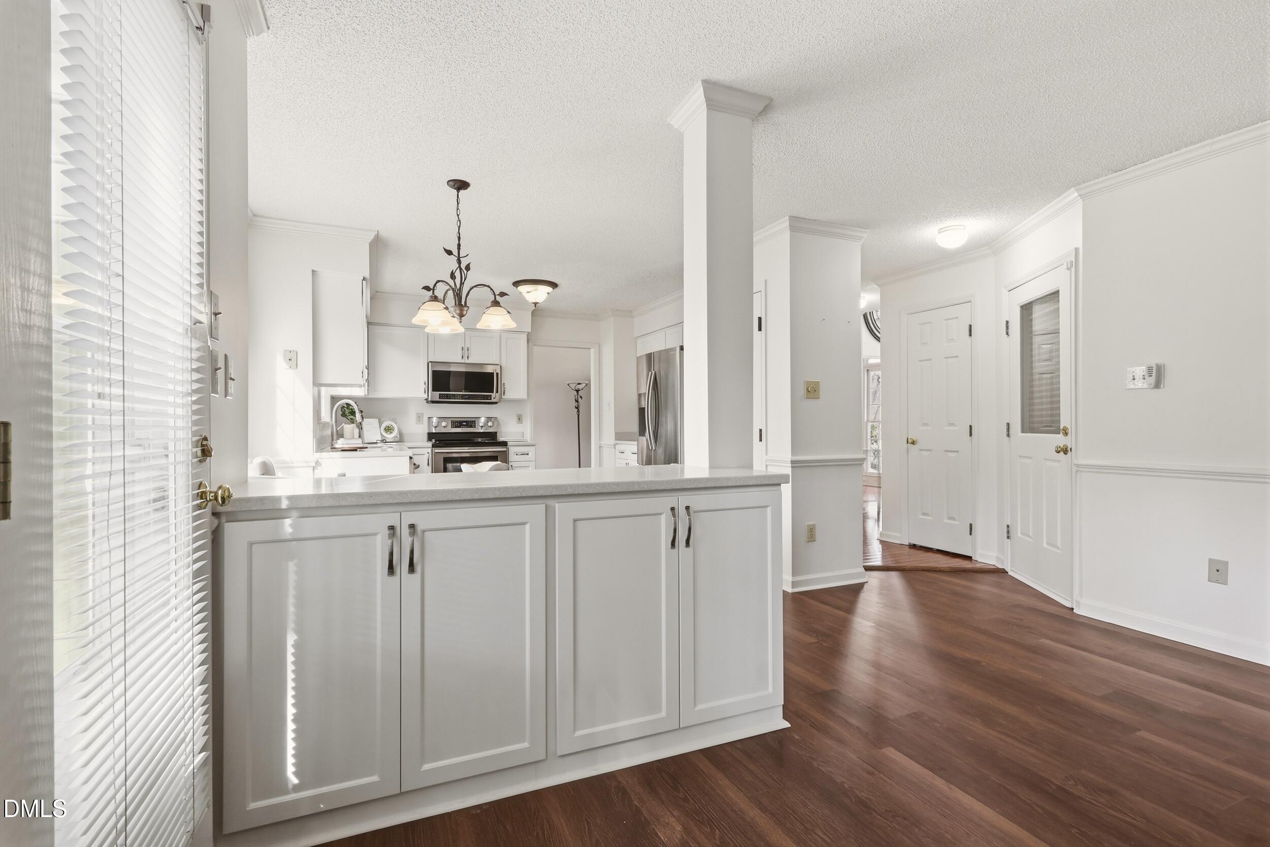 107 Canyon Run Cary, NC 27513 - Photo 22 of 43 a large white kitchen with granite countertop a white stove a sink and dishwasher with wooden floor