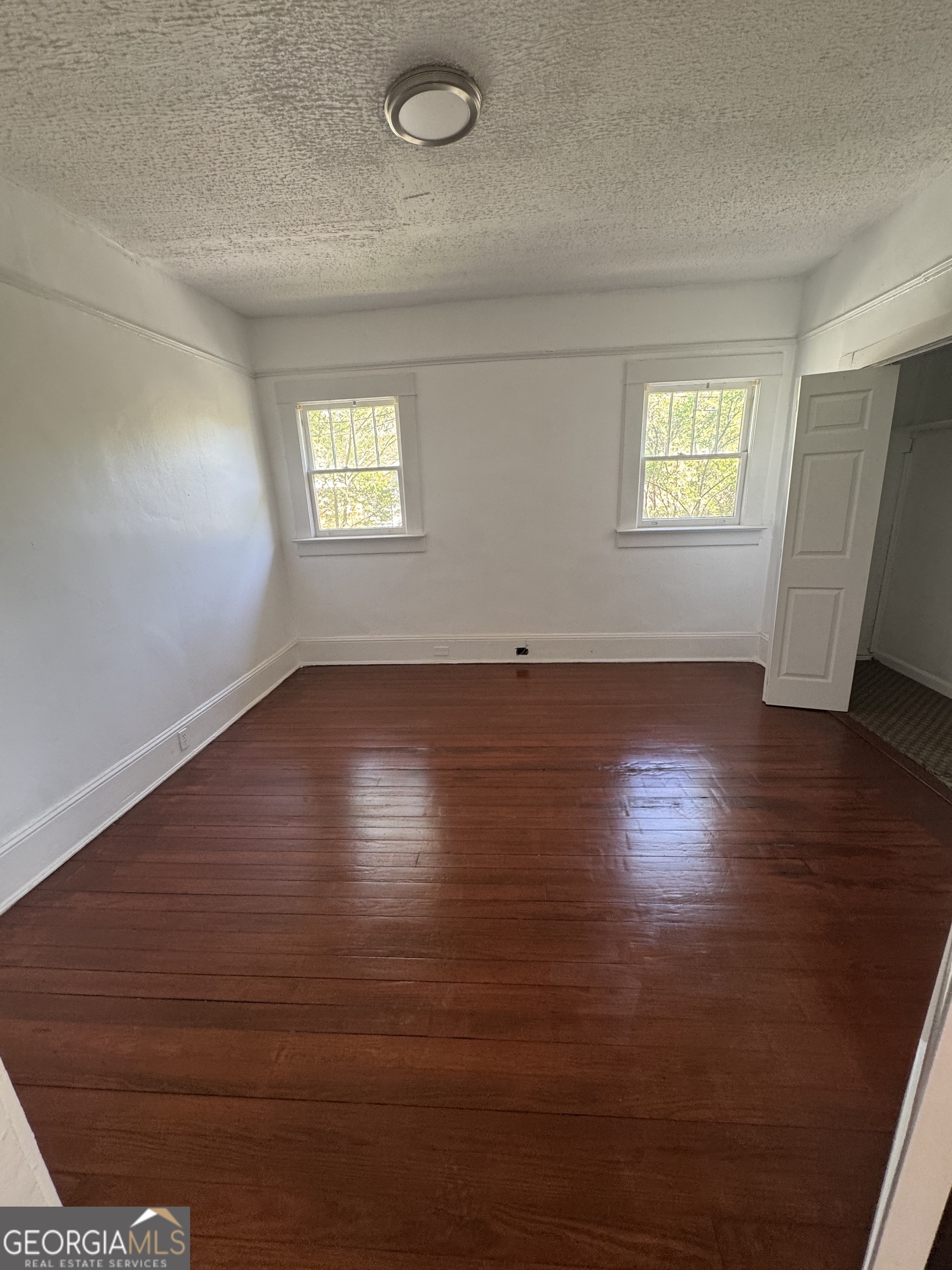 415 Hopkins Street Southwest Atlanta, GA 30310 - Photo 5 of 12 an empty room with wooden floor and windows