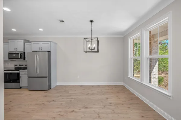 a view of a kitchen with a refrigerator stove a kitchen island cabinets and wooden floor
