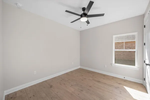 an empty room with a window and a fan