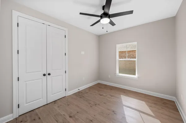 an empty room with wooden floor closet and windows