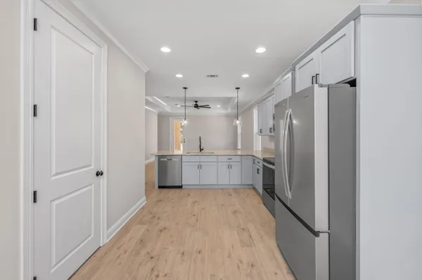 a large white kitchen with a refrigerator a sink and cabinets
