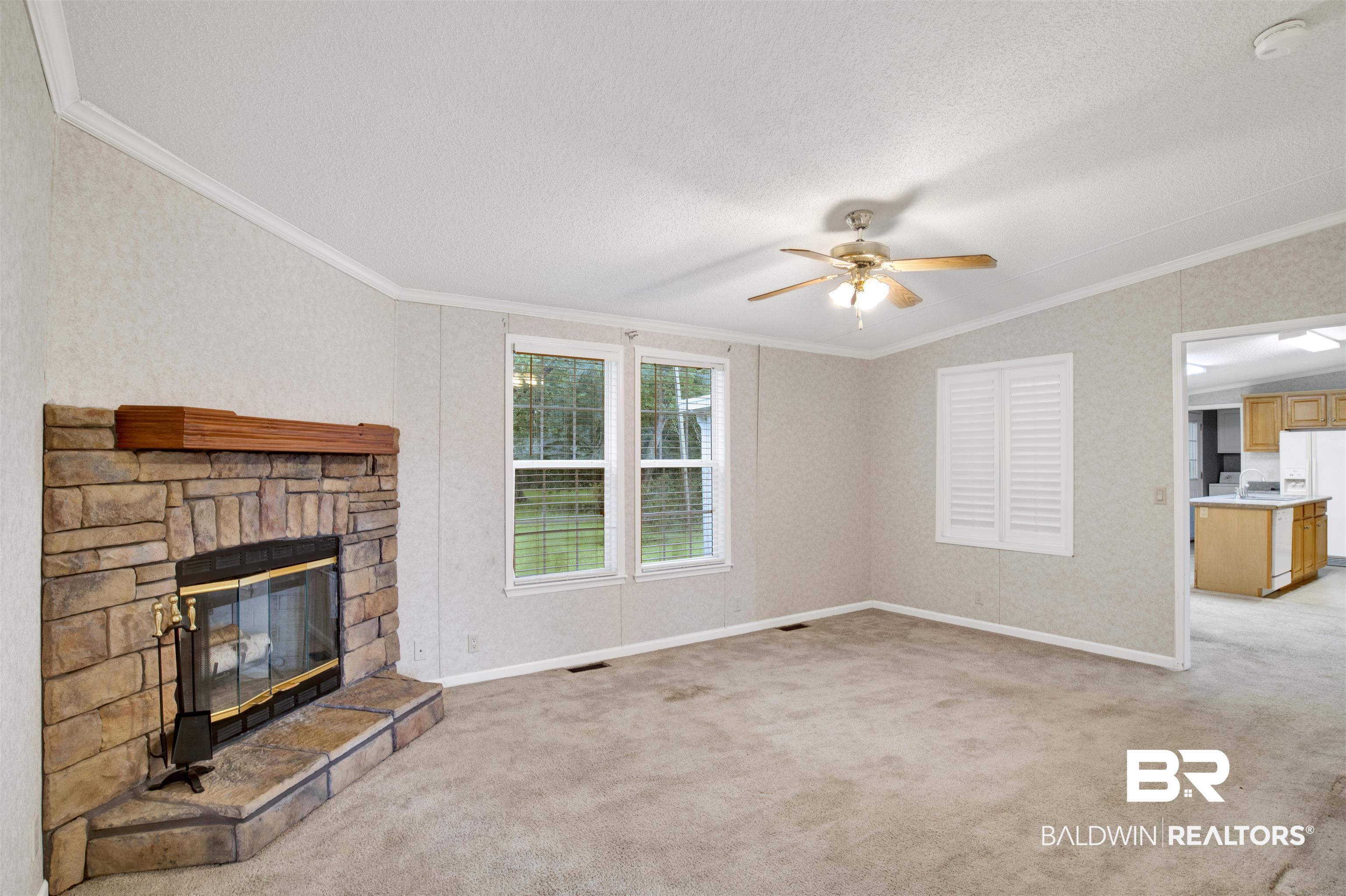 25700 County Road 71 Robertsdale, AL 36567 - Photo 14 of 40 Unfurnished living room with crown molding, light colored carpet, a textured ceiling, a ceiling fan, and vaulted ceiling