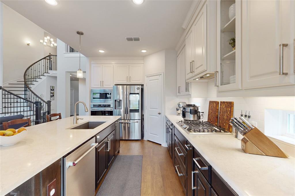 1997 Kieva Place Allen, TX 75013 - Photo 11 of 40 Kitchen with stainless steel appliances, two tone cabinets, glass fronted cabinets, light wood finished floors, and light stone counters
