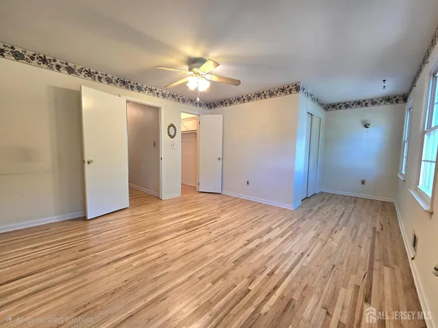 a view of empty room with wooden floor and fan