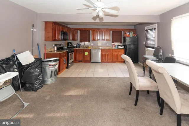a large kitchen with stainless steel appliances granite countertop a stove top oven a sink a dining table and chairs