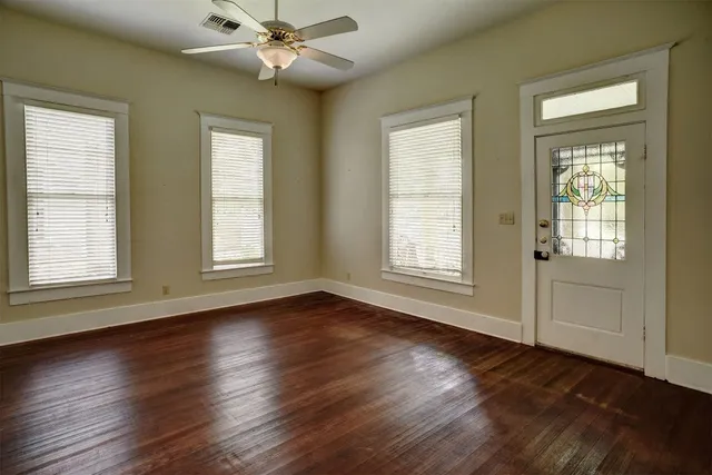 a view of an empty room with wooden floor and a window
