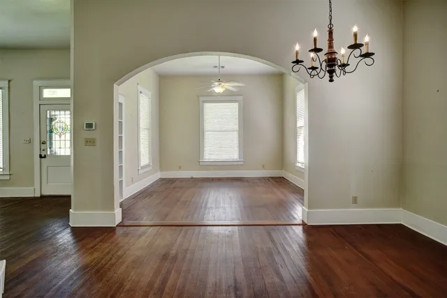 an empty room with wooden floor and hallway