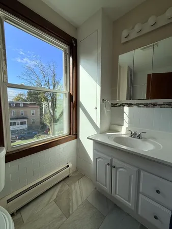 a bathroom with a granite countertop sink and large window