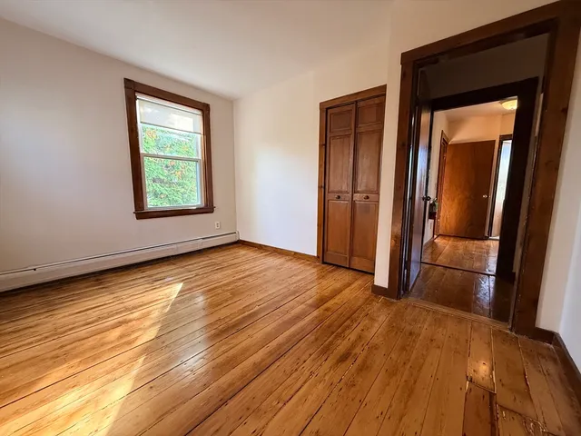 an empty room with wooden floor and a window