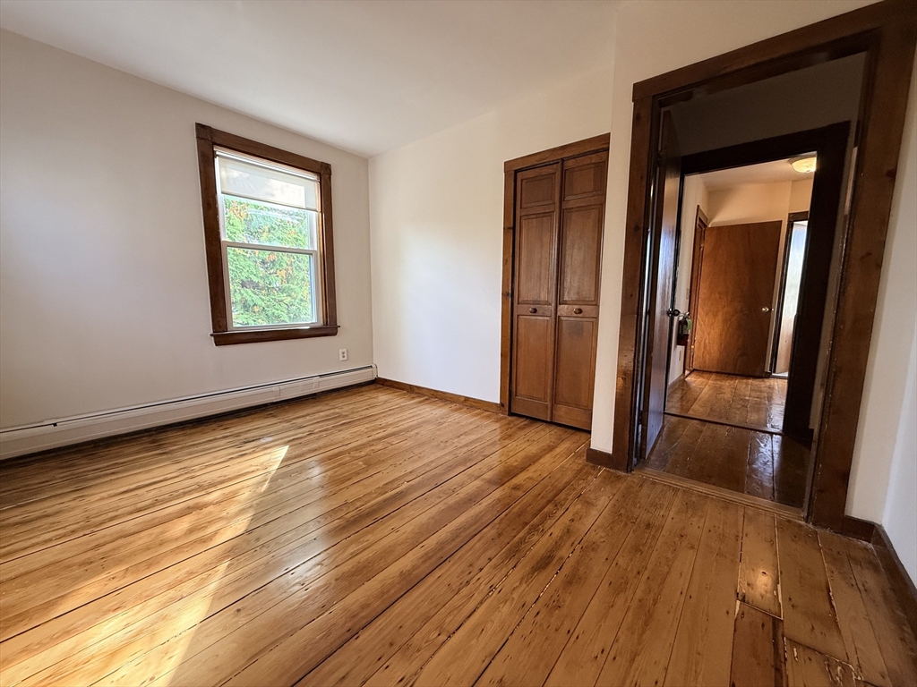 5 Oakland Street, Unit 1 Boston, MA 02119 - Photo 13 of 25 an empty room with wooden floor and a window