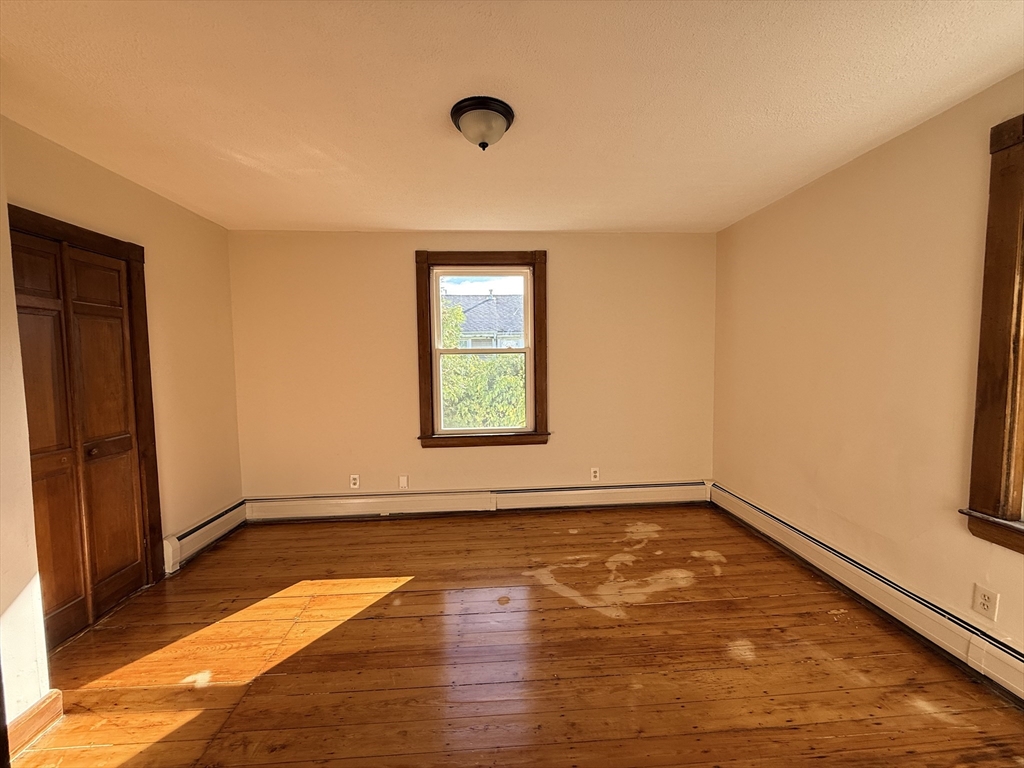 5 Oakland Street, Unit 1 Boston, MA 02119 - Photo 16 of 25 an empty room with wooden floor and windows