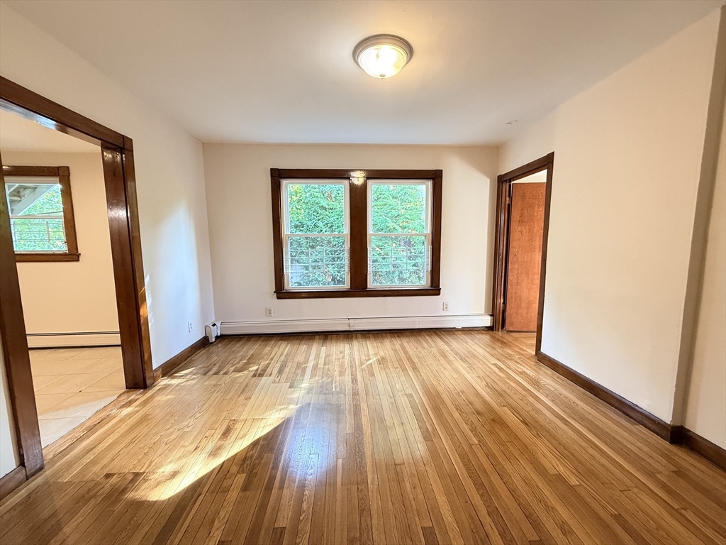5 Oakland Street, Unit 1 Boston, MA 02119 - Photo 4 of 25 an empty room with wooden floor and windows