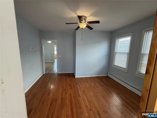 a view of empty room with wooden floor and fan