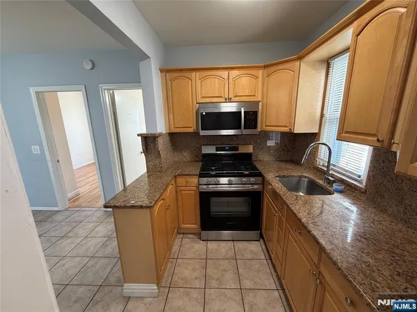 a kitchen with stainless steel appliances granite countertop a stove a sink and a microwave