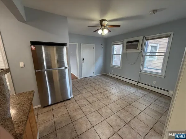 a view of an empty room with window and chandelier fan