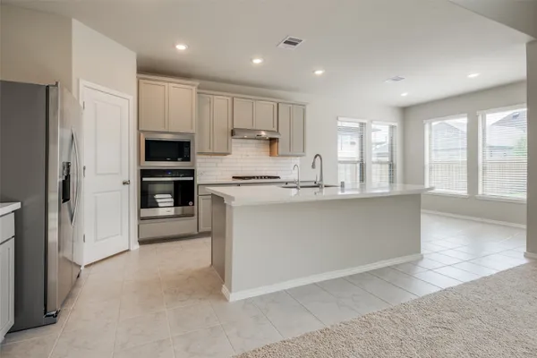 a living room with stainless steel appliances kitchen island furniture and windows