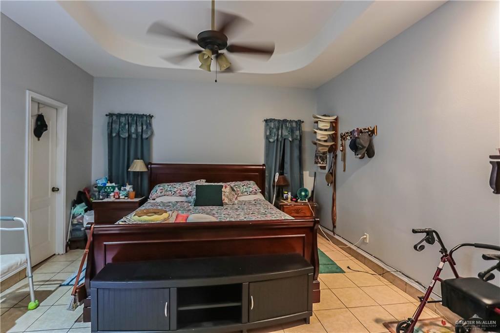 4701 Russell Circle Mission, TX 78574 - Photo 14 of 41 Bedroom with light tile patterned floors, ceiling fan, and a raised ceiling