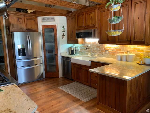 1061 Copper Street Stockton, UT 84071 - Photo 11 of 43 Well-appointed kitchen featuring wood-finish flooring, natural wood cabinetry, light-toned countertops, and a brick-patterned backsplash