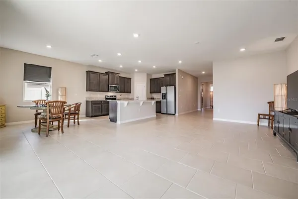 a view of kitchen with stainless steel appliances refrigerator stove dining table and chairs