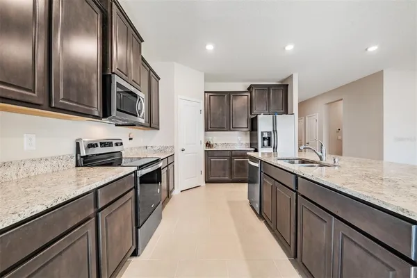 a large kitchen with stainless steel appliances granite countertop a sink a stove top oven and refrigerator