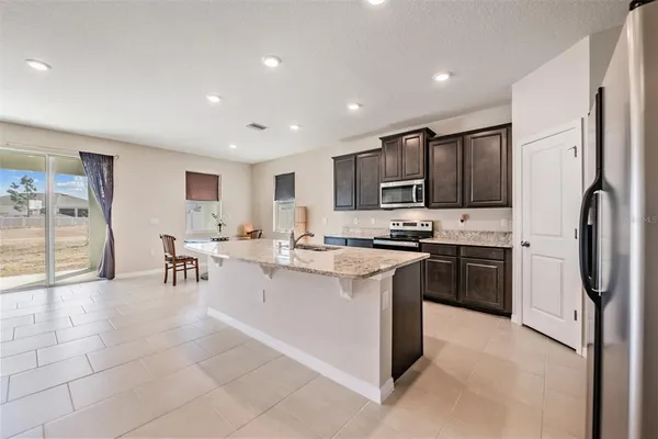 a kitchen with stainless steel appliances granite countertop a refrigerator oven a sink a dining table and chairs