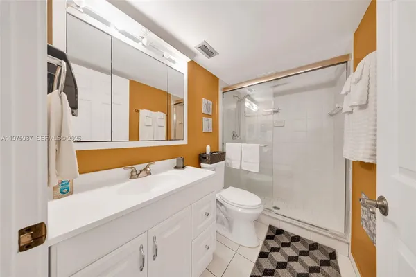 a bathroom with a sink a toilet a mirror a vanity and shower