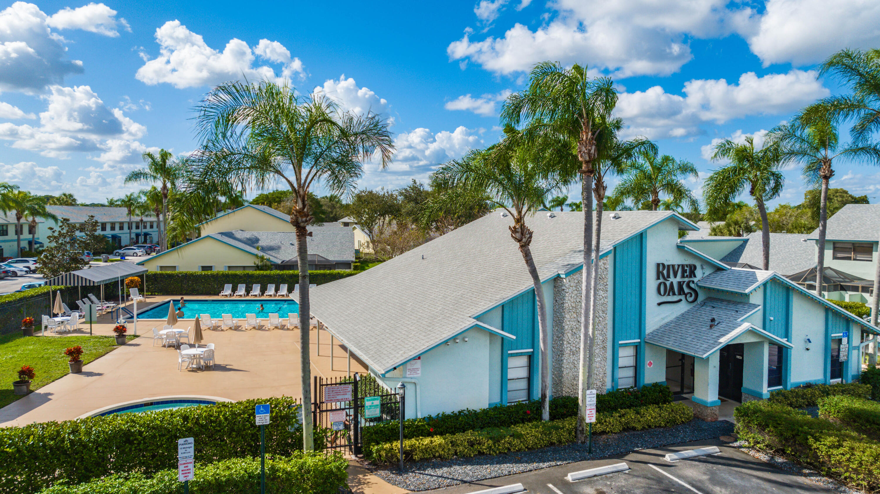 9142 Southwest 22nd Street, Unit E Boca Raton, FL 33428 - Photo 45 of 51 a view of a white house with a yard and table and chairs under an umbrella