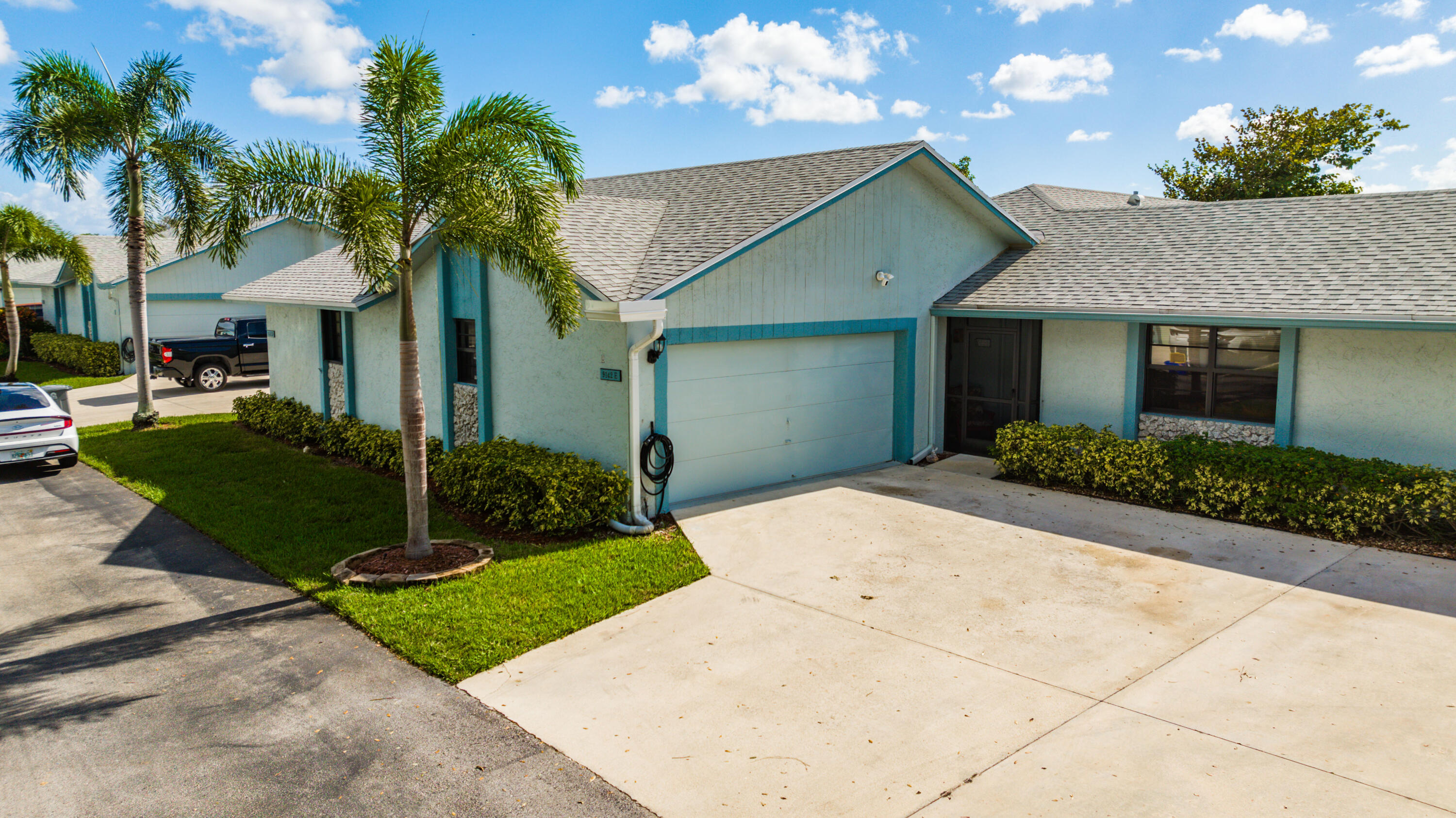 9142 Southwest 22nd Street, Unit E Boca Raton, FL 33428 - Photo 51 of 51 a front view of a house with a garden and trees