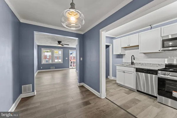 a view of a kitchen with stainless steel appliances granite countertop a stove top oven a sink dishwasher and cabinets with wooden floor