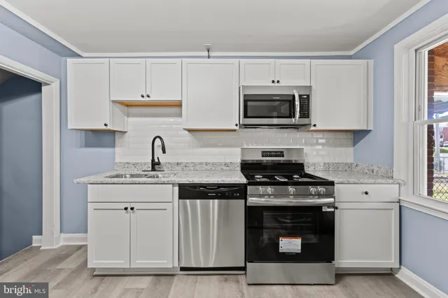 a kitchen with stainless steel appliances granite countertop a stove a sink and a microwave