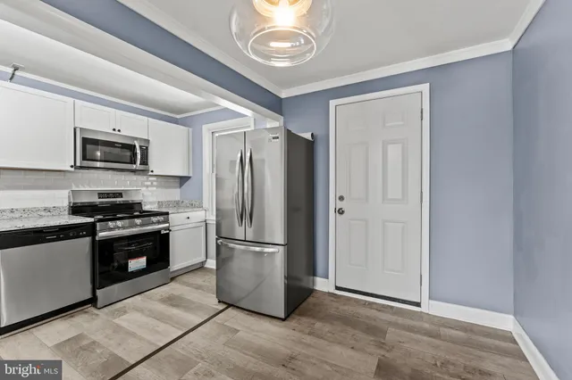 a kitchen with granite countertop a refrigerator and a stove top oven