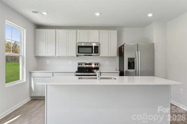 a kitchen with stainless steel appliances a refrigerator a stove a microwave a sink and cabinets