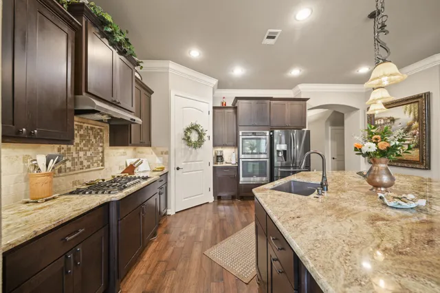 a kitchen with stainless steel appliances granite countertop sink stove refrigerator and cabinets