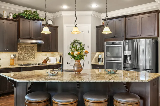 a kitchen with granite countertop a sink a stove and refrigerator