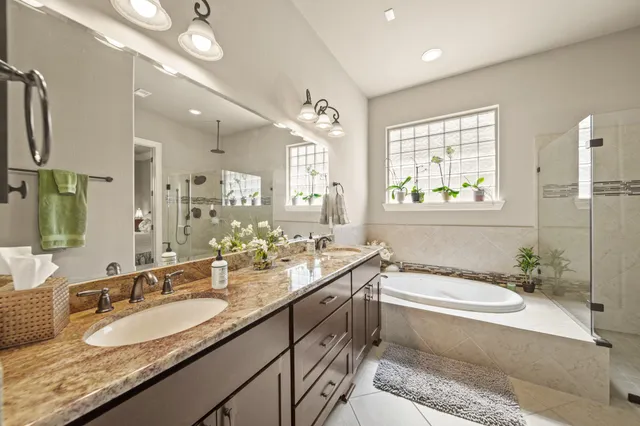 a bathroom with a granite countertop bathtub double vanity sink and a large mirror